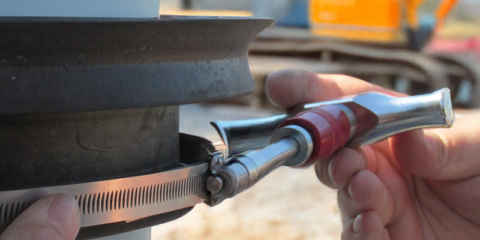 Hand putting a metal clamp on a rubber connector