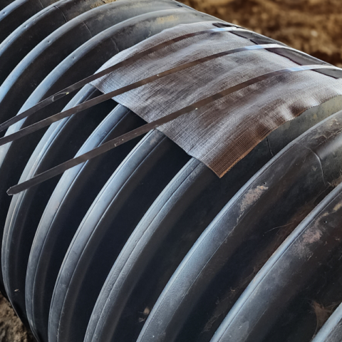 Black corrugated plastic pipe with a gray tape like substance