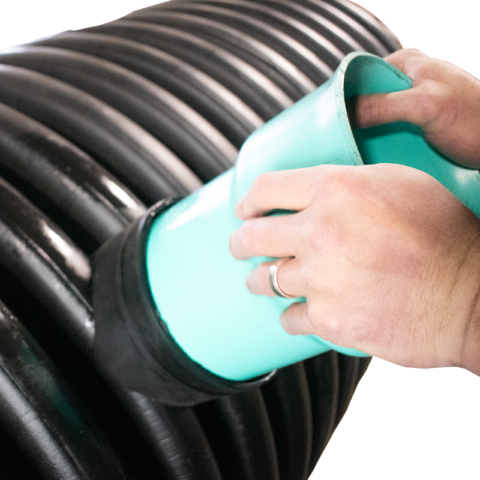 Males hands inserting a PVC hub into a black plastic pipe