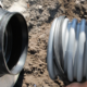 Dirt background in a ditch with a rubber gasket being pulled over a ribbed pipe